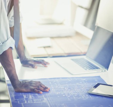 Ofiste bilgisayar ve planlarla çalışan Afrikalı Amerikalı bir mimar.