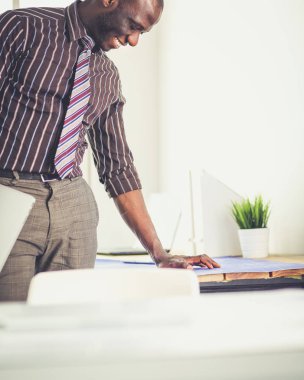 Ofiste bilgisayar ve planlarla çalışan Afrikalı Amerikalı bir mimar.