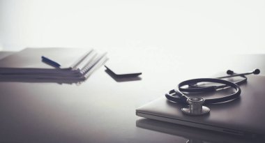 Dizüstü bilgisayarı, steteskopu ve defteri olan bir doktorun çalışma yeri.