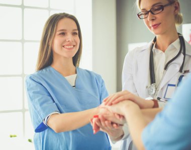 Doktorlar ve hemşireler tıbbi bir ekipte el ele tutuşuyorlar.