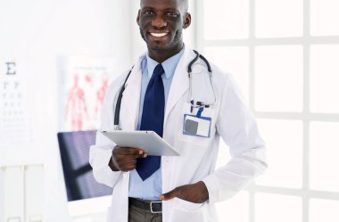 Tablet bilgisayarlı siyahi bir doktor hastanede bekliyor.
