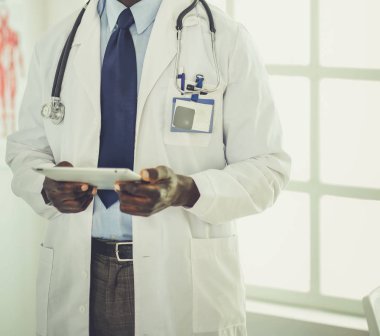Tablet bilgisayarlı siyahi bir doktor hastanede bekliyor.
