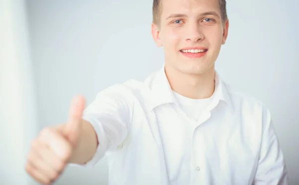 Portret van de jonge man die lacht zittend op een grijze achtergrond. Portret van jonge man — Stockfoto