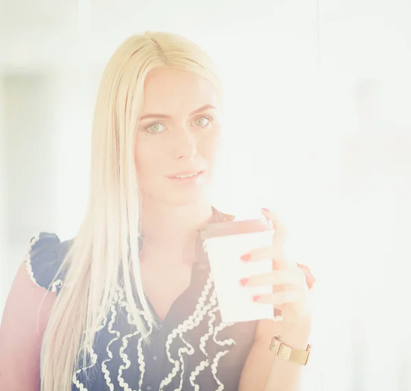 Businesswoman holding a cup of coffee standing in office . — Stock Photo, Image