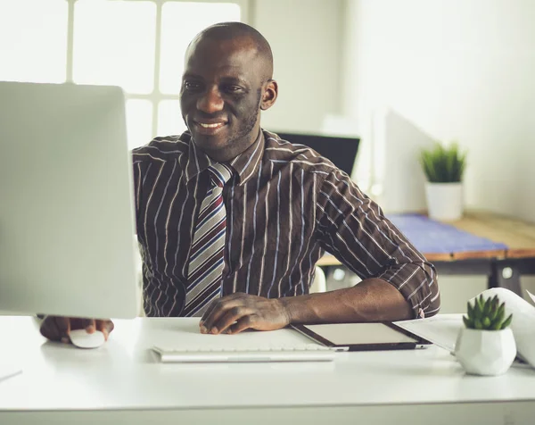 Yakışıklı Afro Amerikalı işadamı Klasik takım elbiseli bir dizüstü bilgisayar kullanarak ve ofiste çalışırken gülümseyen — Stok fotoğraf