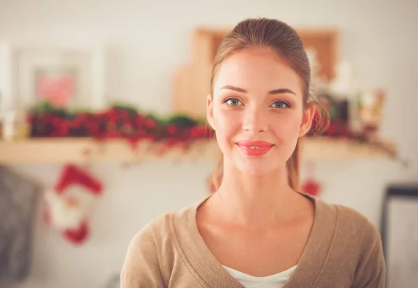 Jeune femme souriante dans la cuisine, isolée sur fond de Noël. — Photo