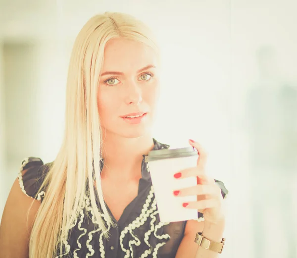 Empresaria sosteniendo una taza de café de pie en la oficina  . — Foto de Stock