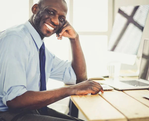 Beau Afro-Américain homme d'affaires en costume classique utilise un ordinateur portable et souriant tout en travaillant au bureau — Photo