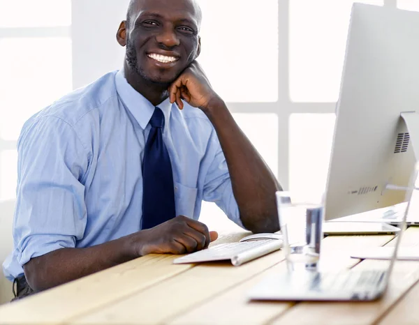 Beau Afro-Américain homme d'affaires en costume classique utilise un ordinateur portable et souriant tout en travaillant au bureau — Photo