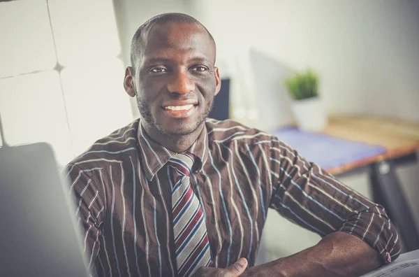 Bello uomo d'affari afro americano in abito classico sta utilizzando un computer portatile e sorridente mentre si lavora in ufficio — Foto Stock