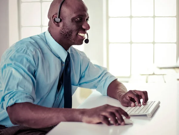 Homme d'affaires afro-américain sur casque de travail sur son ordinateur portable — Photo