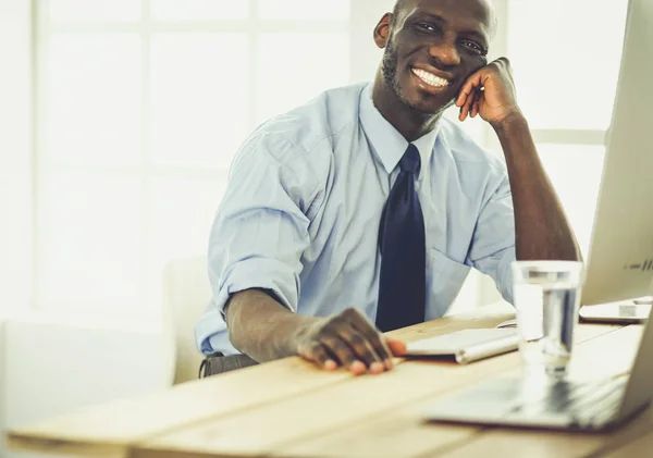 Handsome afro american businessman in classic suit is using a laptop and smiling while working in office — Stock Photo, Image