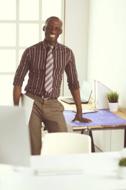 Ofiste bilgisayar ve planlarla çalışan Afrikalı Amerikalı bir mimar.