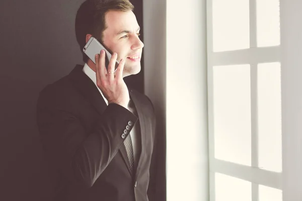Handsome businessman talking on mobile phone in modern office. — Stock Photo, Image