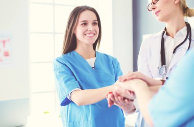 Doktorlar ve hemşireler tıbbi bir ekipte el ele tutuşuyorlar.