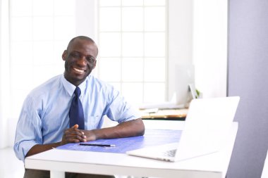 Ofiste bilgisayar ve planlarla çalışan Afrikalı Amerikalı bir mimar.