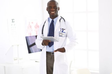 Tablet bilgisayarlı siyahi bir doktor hastanede bekliyor.