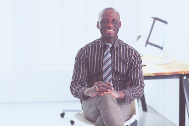 Yakışıklı Afro Amerikalı işadamı Klasik takım elbiseli bir dizüstü bilgisayar kullanarak ve ofiste çalışırken gülümseyen