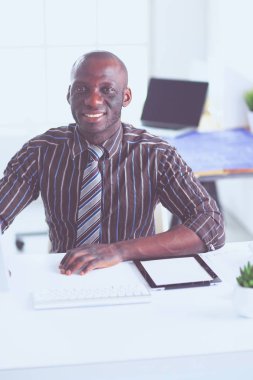 Yakışıklı Afro Amerikalı işadamı Klasik takım elbiseli bir dizüstü bilgisayar kullanarak ve ofiste çalışırken gülümseyen