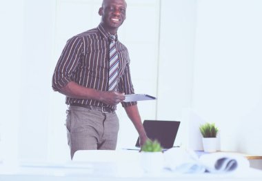 Ofiste bilgisayar ve planlarla çalışan Afrikalı Amerikalı bir mimar.