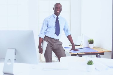 Ofiste bilgisayar ve planlarla çalışan Afrikalı Amerikalı bir mimar.