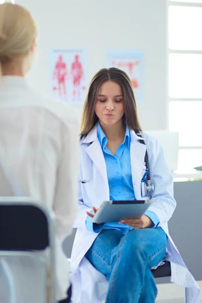 Doktorn och patienten diskuterar något när de sitter vid bordet. Medicin och hälsovård — Stockfoto