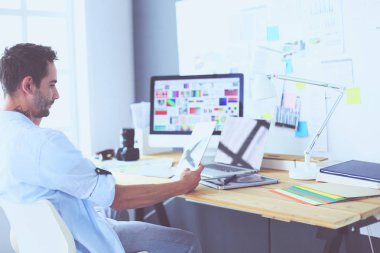 İnternette çalışırken bilgisayarın ve dizüstü bilgisayarın önünde grafik stüdyosunda oturan genç tasarımcının portresi.