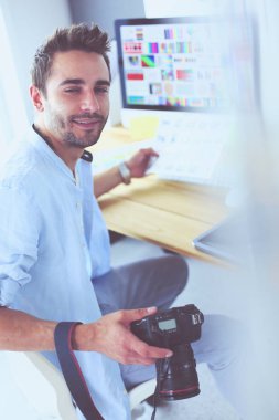 İnternette çalışırken bilgisayarın ve dizüstü bilgisayarın önünde grafik stüdyosunda oturan genç tasarımcının portresi.