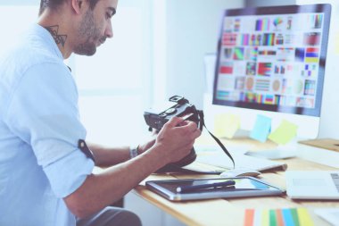 İnternette çalışırken bilgisayarın ve dizüstü bilgisayarın önünde grafik stüdyosunda oturan genç tasarımcının portresi.