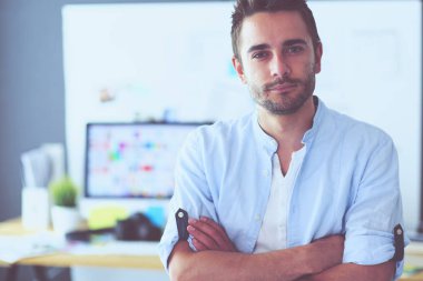 Dizüstü bilgisayar ve bilgisayar çalışırken önünde genç tasarımcı portresi. Onun mobil arka plan kullanarak Yardımcısı.