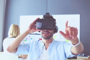 Genç erkek yazılım programcısı ofiste üç boyutlu sanal gerçeklik gözlükleriyle yeni bir uygulama test ediyor..