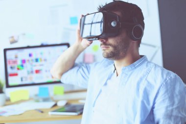 Genç erkek yazılım programcısı ofiste üç boyutlu sanal gerçeklik gözlükleriyle yeni bir uygulama test ediyor..