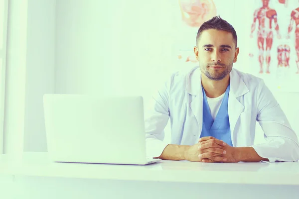 Retrato de un médico varón con portátil sentado en el escritorio en el consultorio médico. — Foto de Stock