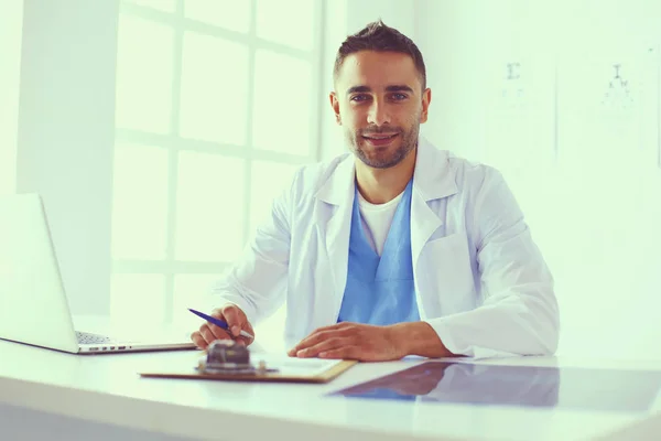 Retrato de un médico varón con portátil sentado en el escritorio en el consultorio médico. — Foto de Stock