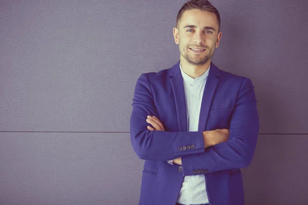 Young businessman sitting isolated on grey background. — Stock Photo, Image