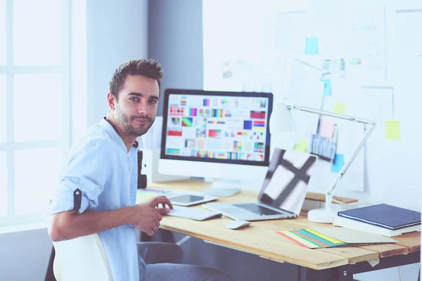 Porträt eines jungen Designers, der im Grafikstudio vor Laptop und Computer sitzt, während er online arbeitet. — Stockfoto