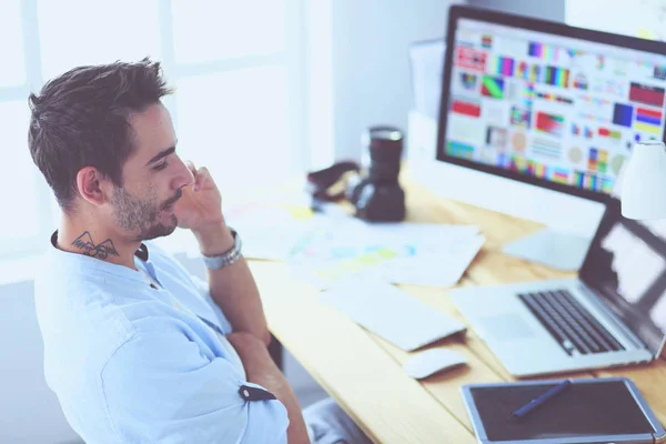 Porträt eines jungen Designers, der im Grafikstudio vor Laptop und Computer sitzt, während er online arbeitet. — Stockfoto