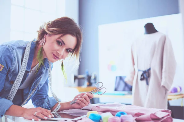 Mulher designer de moda trabalhando com ipad em seus projetos no estúdio — Fotografia de Stock