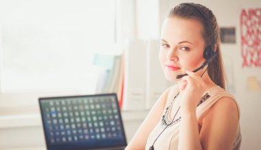 Masasında kulaklığı ve laptopuyla çalışan güzel bir iş kadını. .