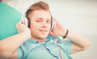 Kanepede müzik dinleyen genç yakışıklı bir adam.