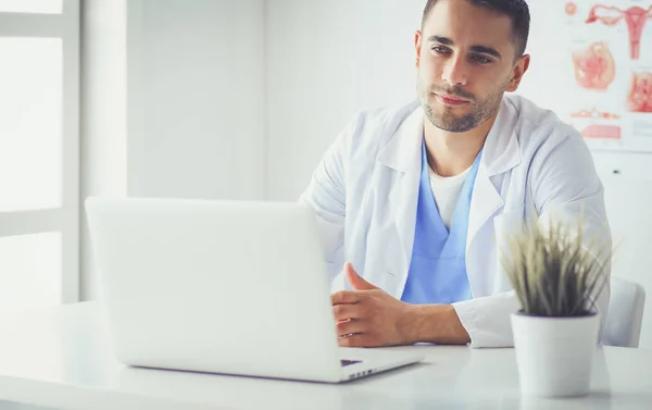 Porträt eines männlichen Arztes mit Laptop am Schreibtisch in der Arztpraxis. — Stockfoto