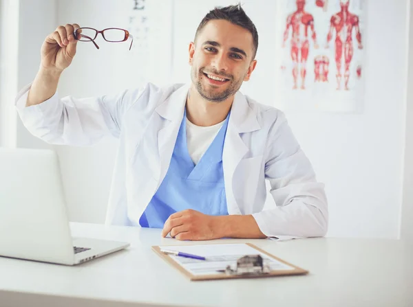 Bilgisayarlı bir erkek doktorun portresi revirde oturuyor.. — Stok fotoğraf