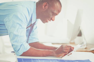 Ofiste bilgisayar ve planlarla çalışan Afrikalı Amerikalı bir mimar.