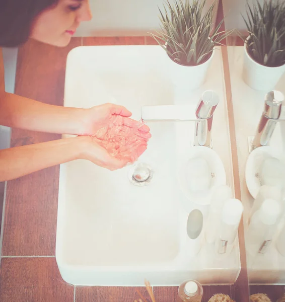 Fiatal nő mossa arcát tiszta vízzel a fürdőszobában — Stock Fotó