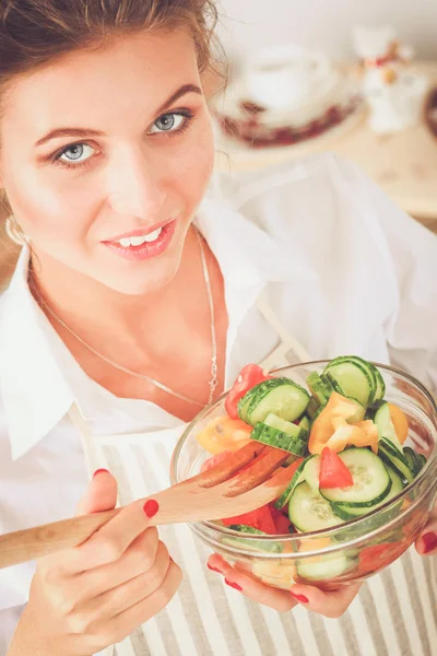 Sorrindo jovem mulher preparando salada na cozinha . — Fotografia de Stock