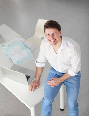 Genç işadamı ofiste çalışıyor, masada oturuyor.