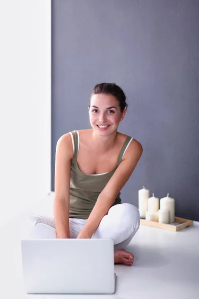 Attraktive kaukasische Mädchen sitzt auf dem Boden mit Tasse und Tablette in der Nähe der Wand — Stockfoto