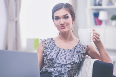 Elinde belgelerle masanın üstünde oturan gülümseyen kadın..