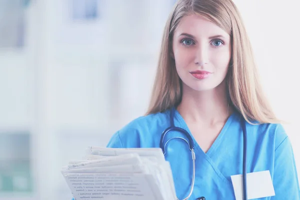 Retrato de doctora con estetoscopio en el pasillo del hospital, sosteniendo una carpeta. — Foto de Stock