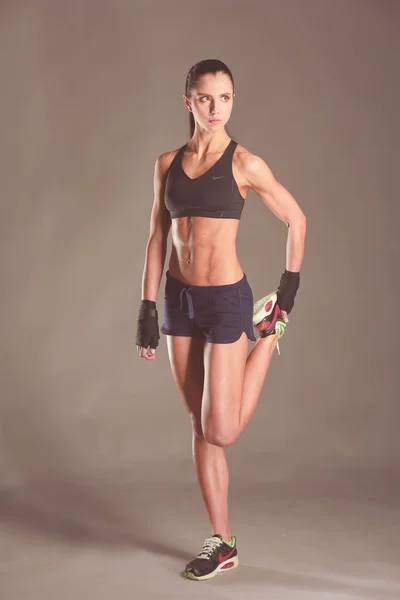 Musculosa joven posando en ropa deportiva sobre fondo negro . — Foto de Stock